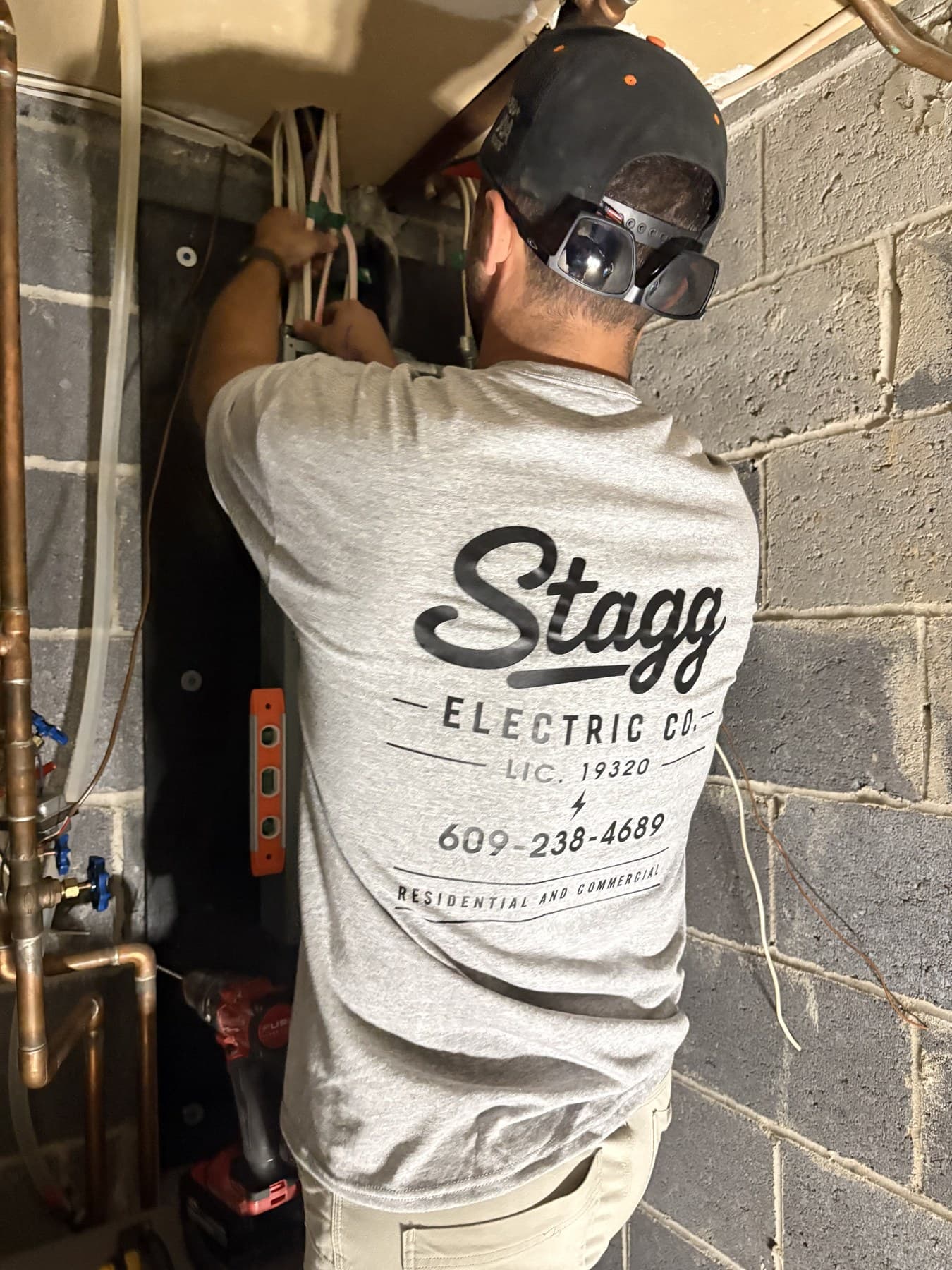 Chris Stagg wiring a panel on a job, in a Stagg Electric shirt