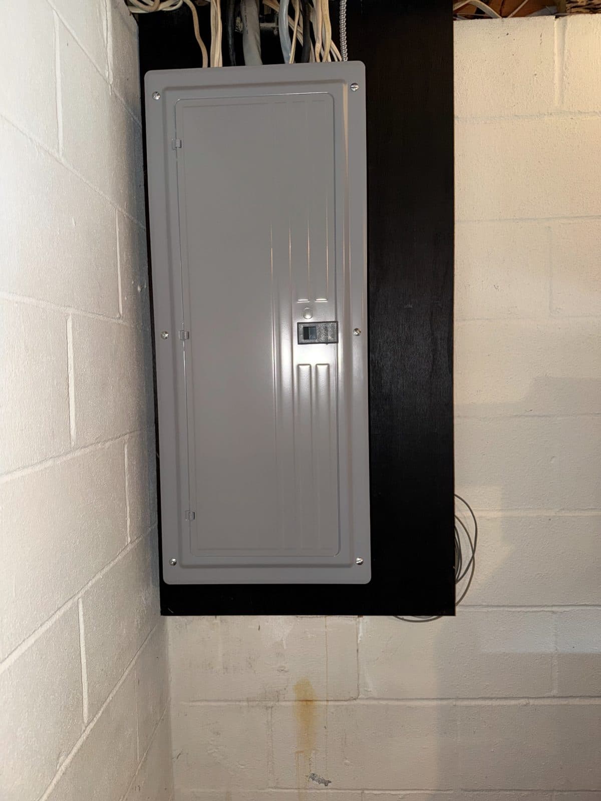 A new electrical panel mounted on a basement block wall in a Berlin house