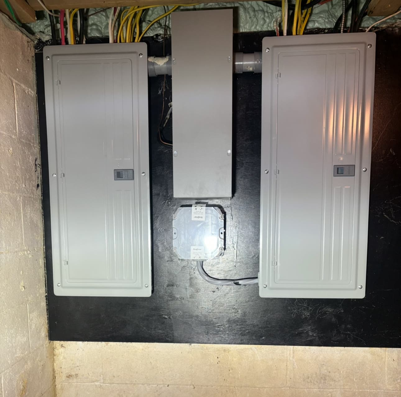 Two new electrical panels mounted side by side on a basement wall, installed by Stagg Electric
